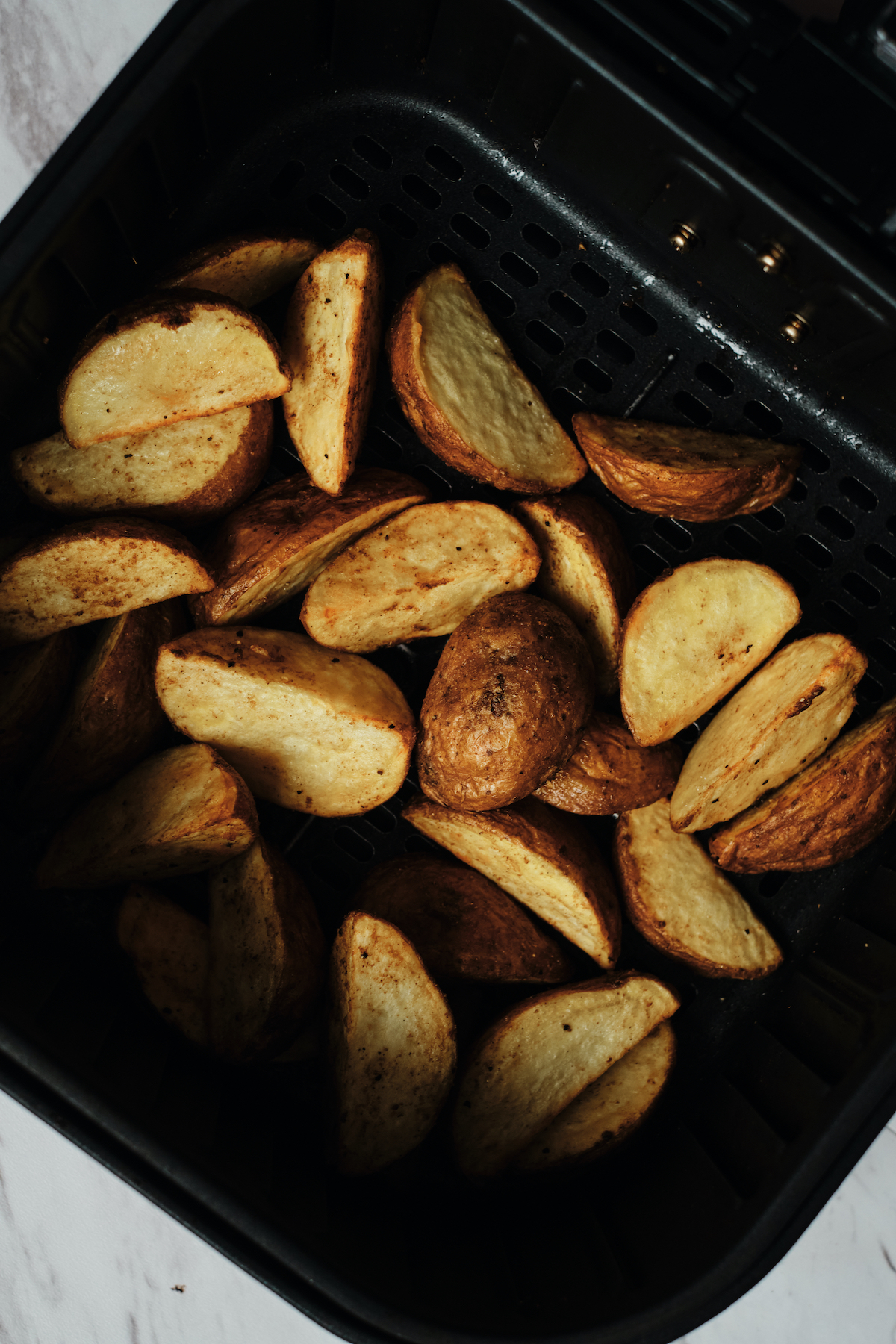 the finished crispy potato wedges inside the air fryer basket