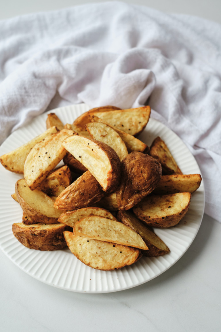 a plate of air fryer potato wedges served with a white cloth napkin