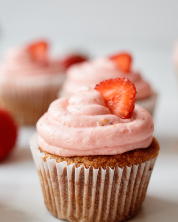 one strawberry churro cupcakes garnished with a strawberry slice