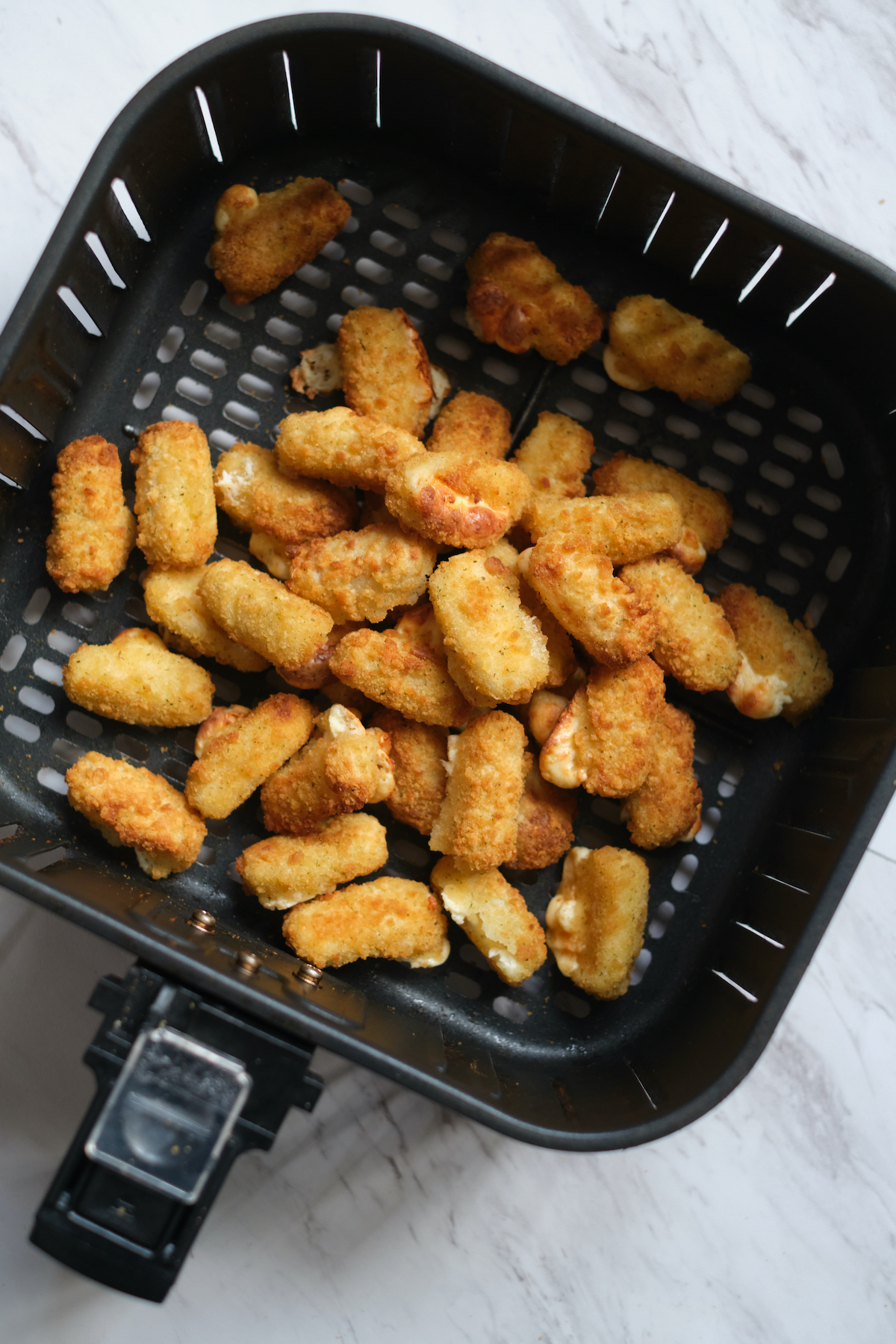 top down view of the cooked mozzarella sticks inside the air fryer basket