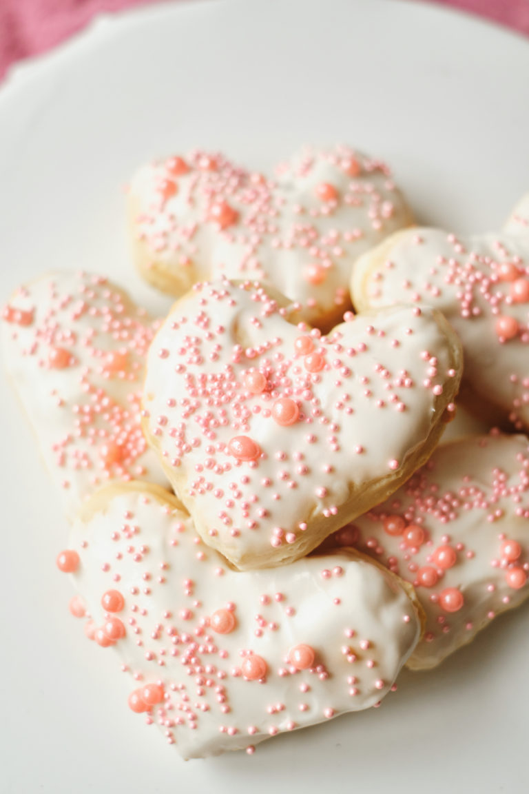 the finished heart shaped donuts piled onto a white plate