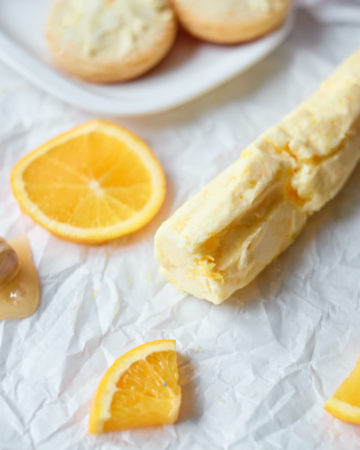 honey butter on parchment paper with orange slices and a biscuit