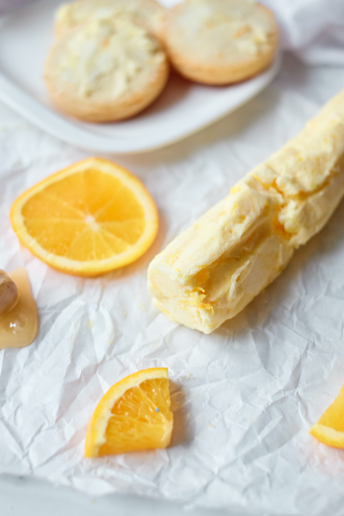 honey butter on parchment paper with orange slices and a biscuit
