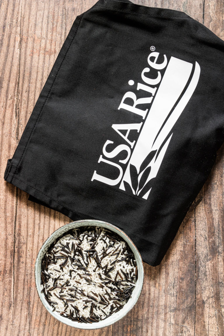 a bowl filled with uncooked wild rice next to a folded USA rice apron
