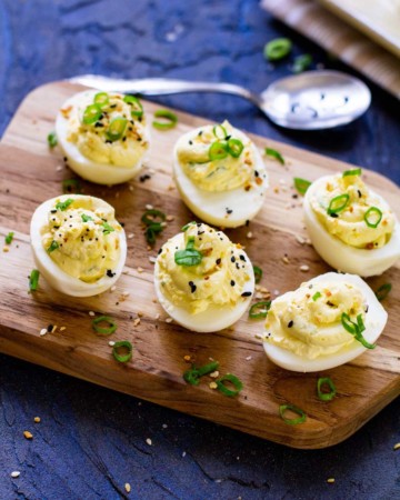 six completed instant pot deviled eggs on a wooden serving board