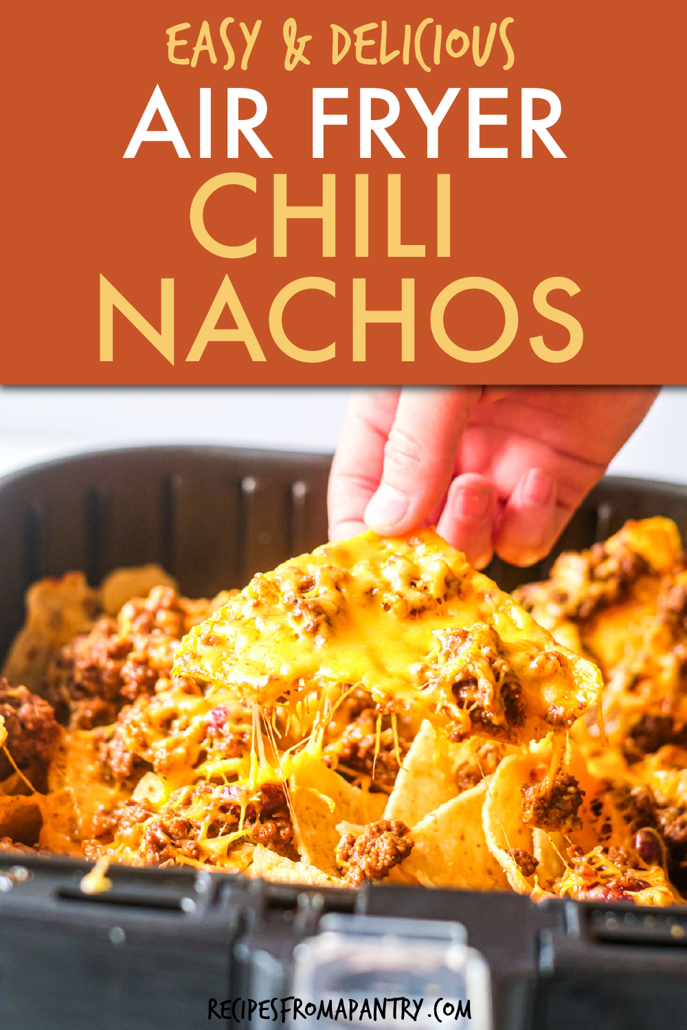 A HAND PULLING A NACHO CHIP OUT OF AN AIR FRYER