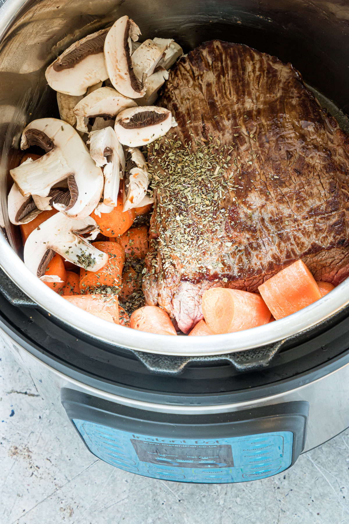 Ingredeints To Make Instant Pot Pot Roast like chuck roast, carrots, and mushrooms in a pressure cooker