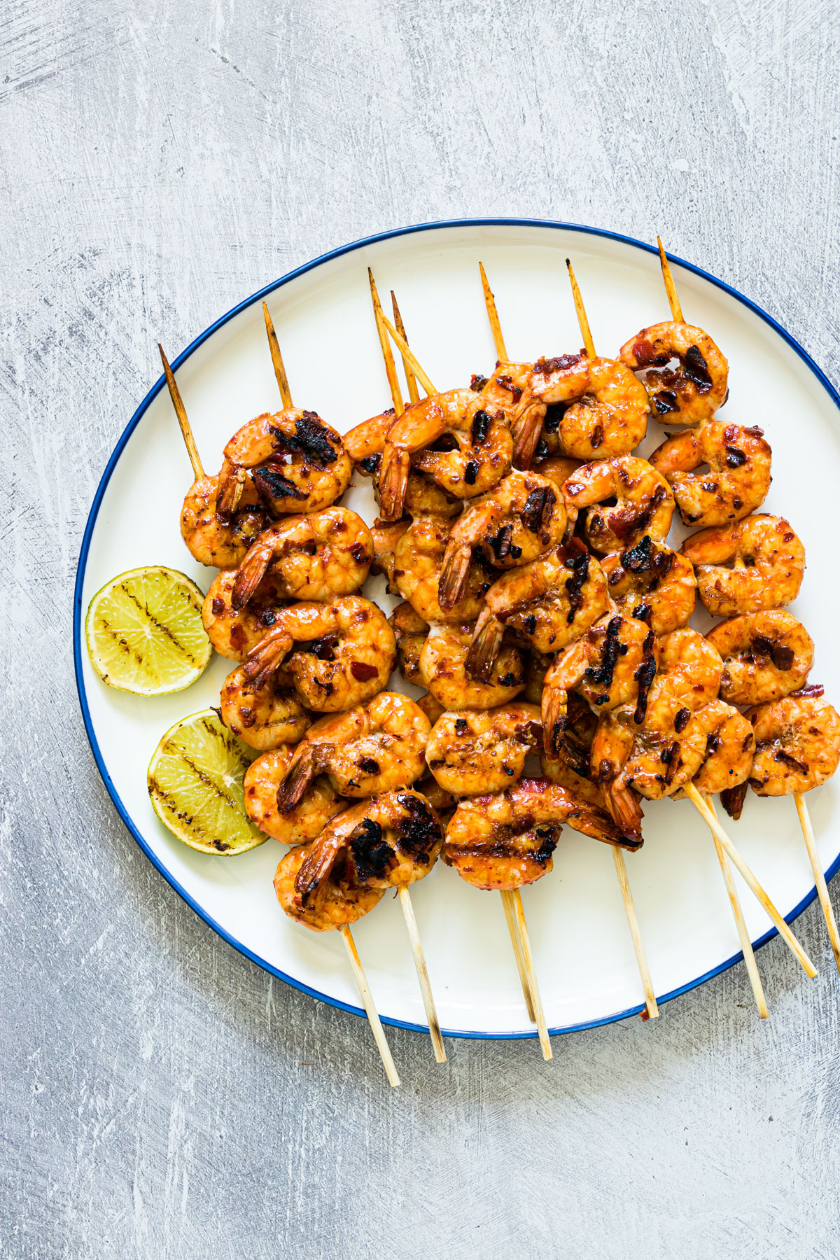 a plate of cooked grilled shrimp skewers with lime slices