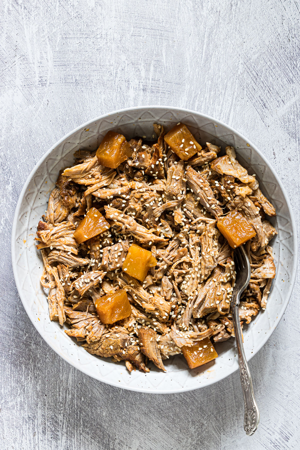 a bowl or instant pot pulled pork with pineapple and sesame seeds 