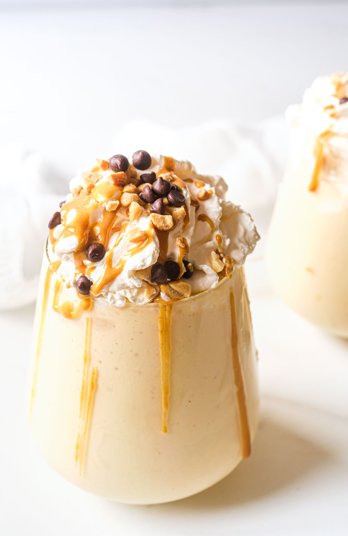 close up of a peanut butter shake with whipped cream, chocolate and peanuts