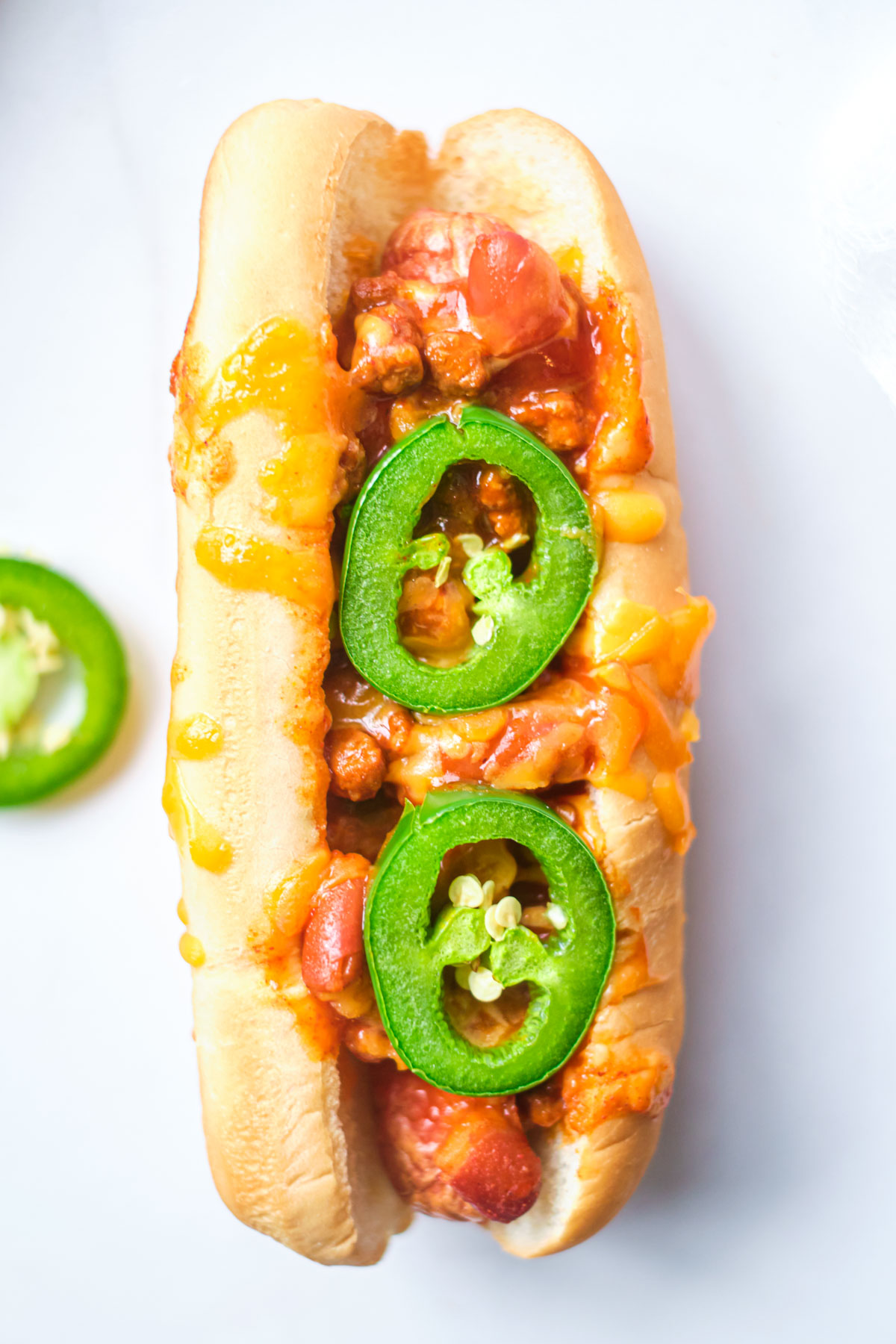 close up of cooked chili cheese dog with melted cheese and jalapeno