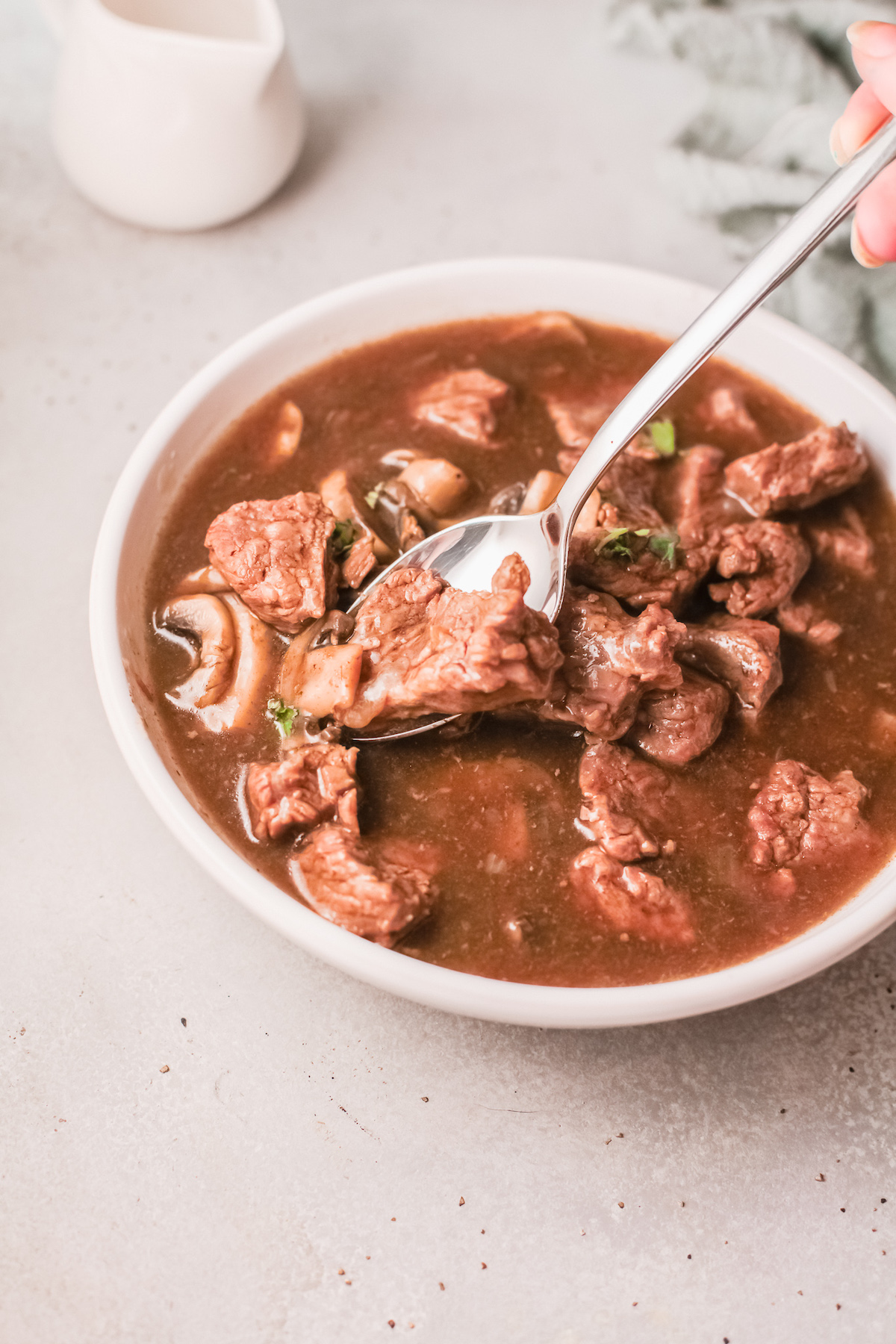 a spoon removing one bite of instant pot beef tips and gravy from a bowl