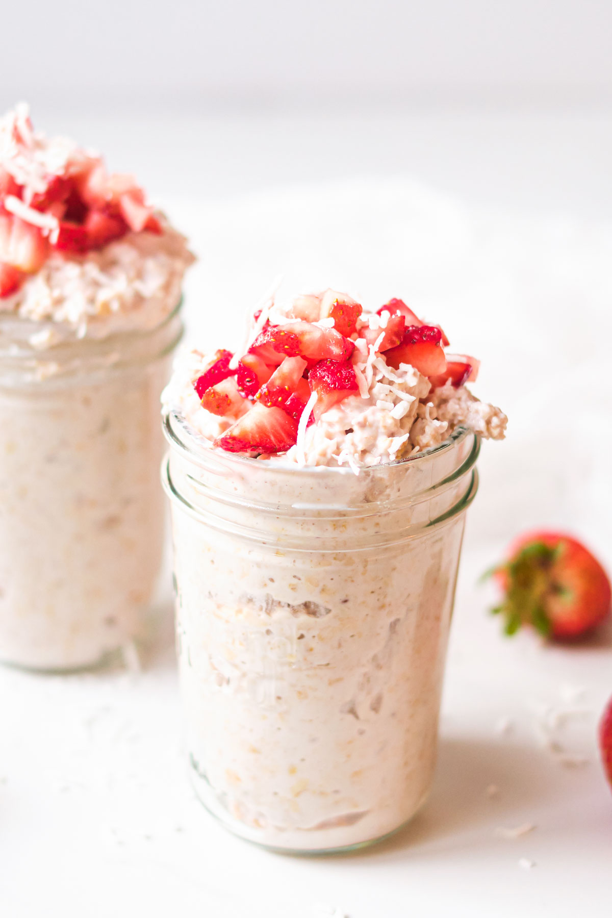 creamy strawberry shortcake overnight oats in a mason jar topped with strawberries and coconut