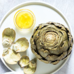 top down view of a completed artichoke served on a white plate