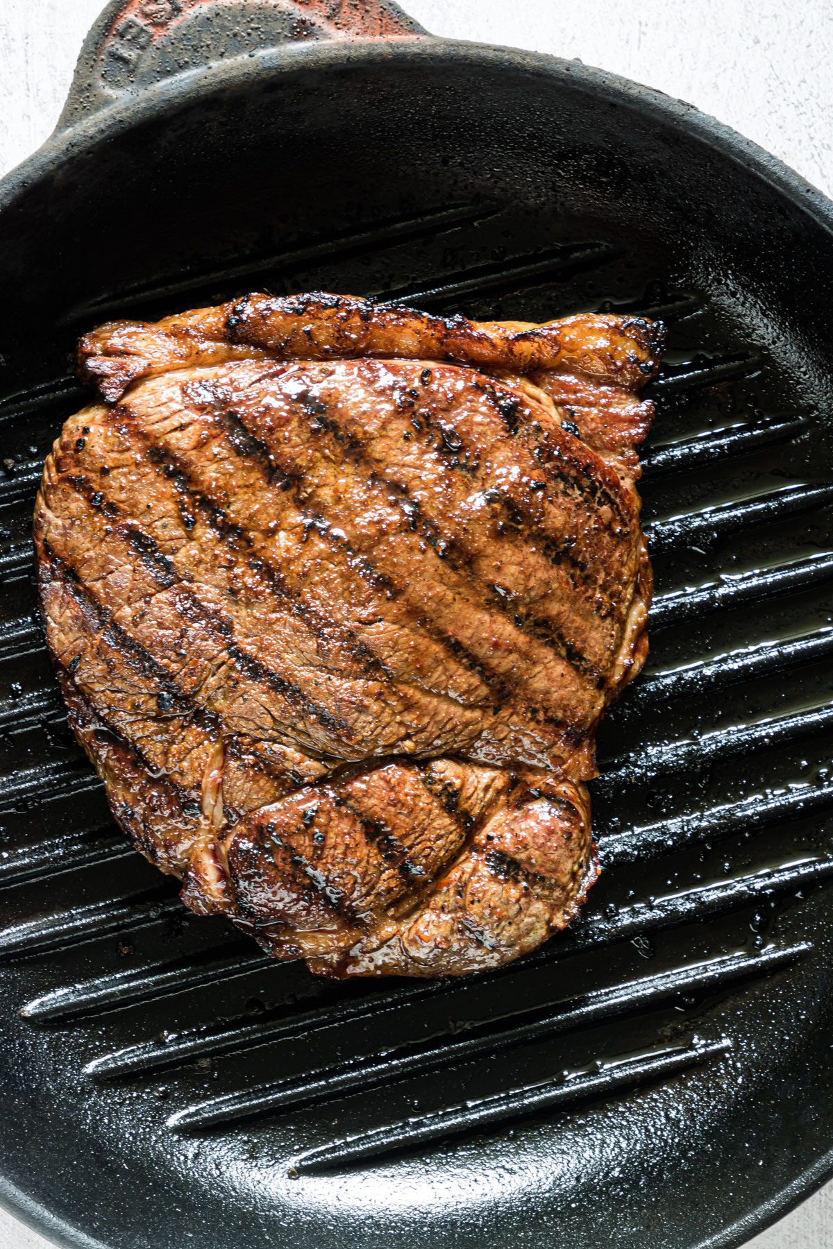 Close up of a juicy grilled steak on a griddle pan.