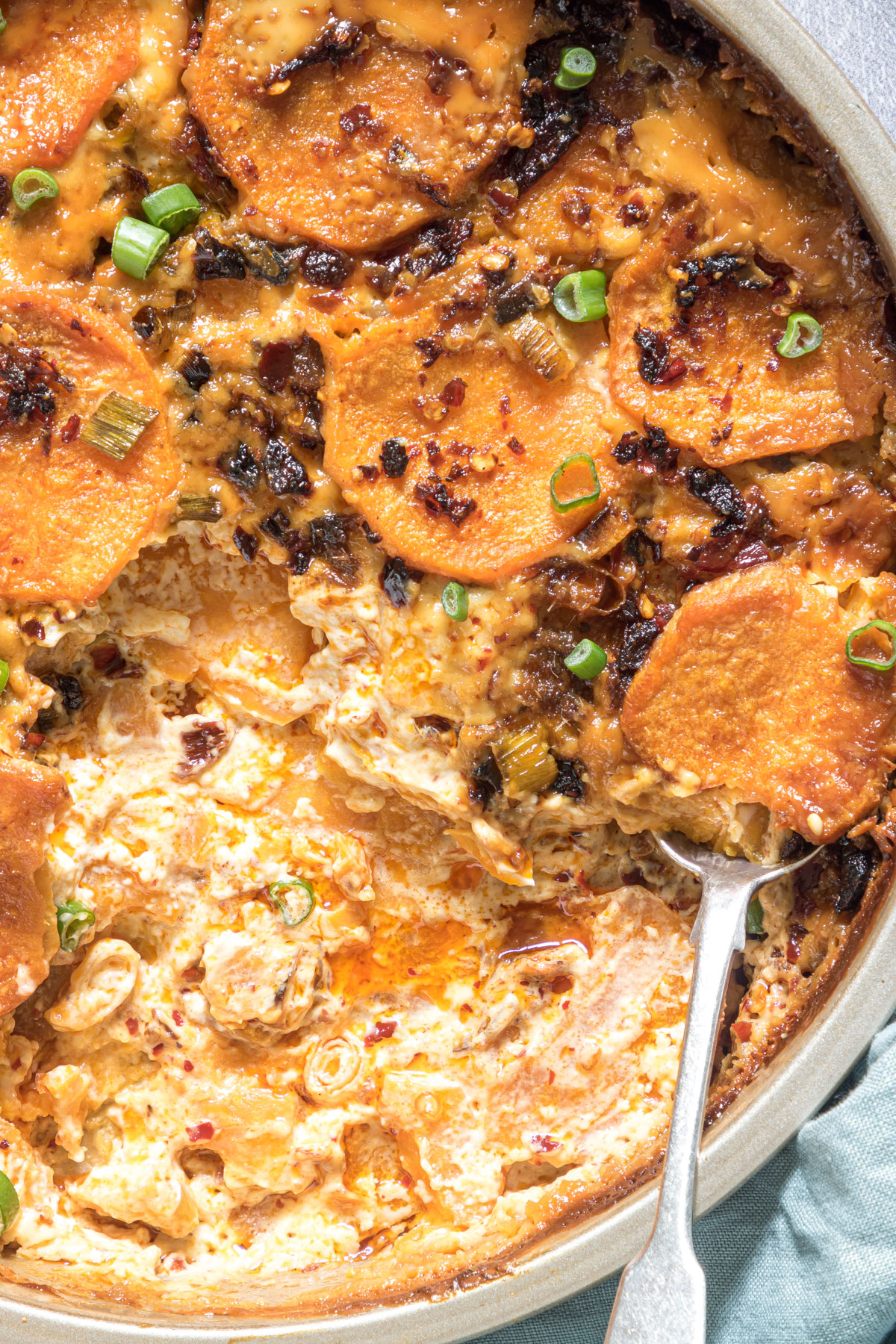 Close up of baked Instant pot sweet potato gratin with some scooped out of the side and a spoon inserted