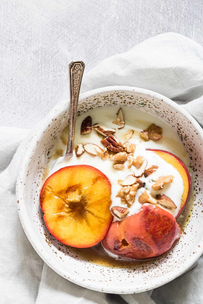 a bowl containing grilled peaches with walnuts and ice cream