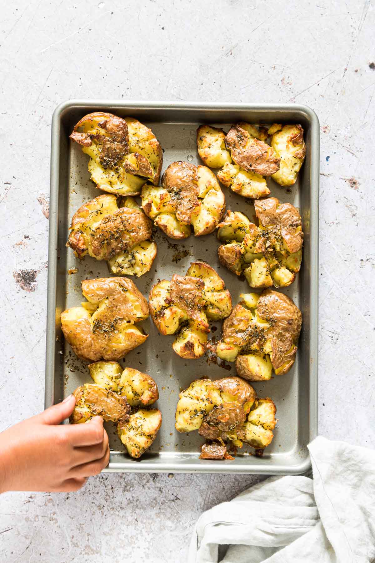 tray of cooked easy smashed potatoes with a hand reaching for one