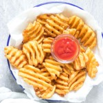 the cooked air fryer frozen waffles fries served in a bowl with a side of ketchup