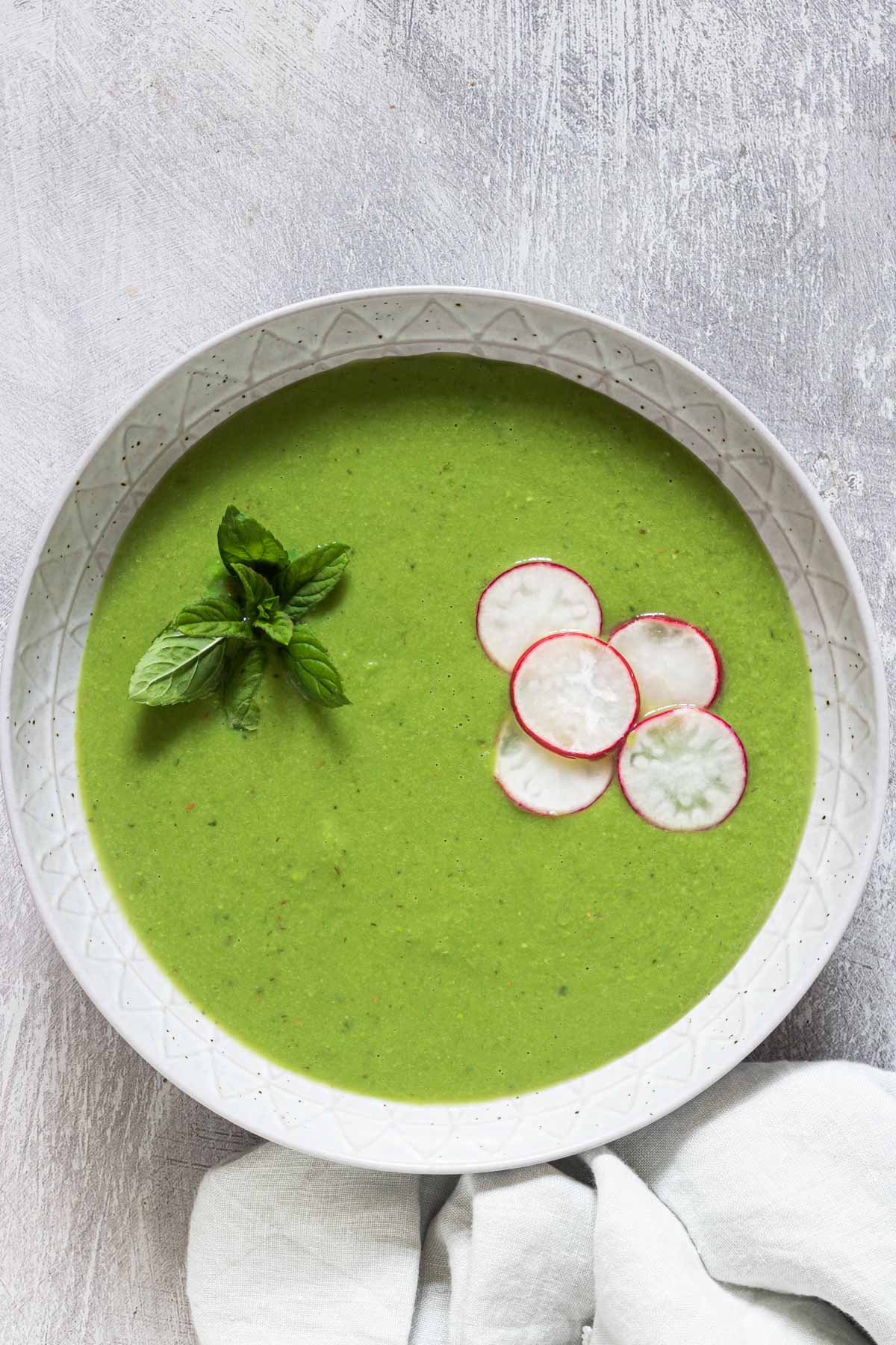 a bowl of pea soup served with a spoon and cloth napkin