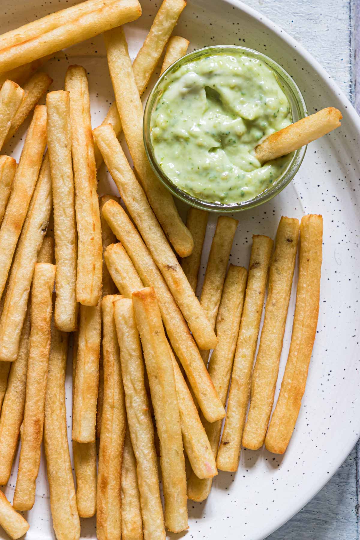 a plate of french fries served with the basil pesto aioli sauce
