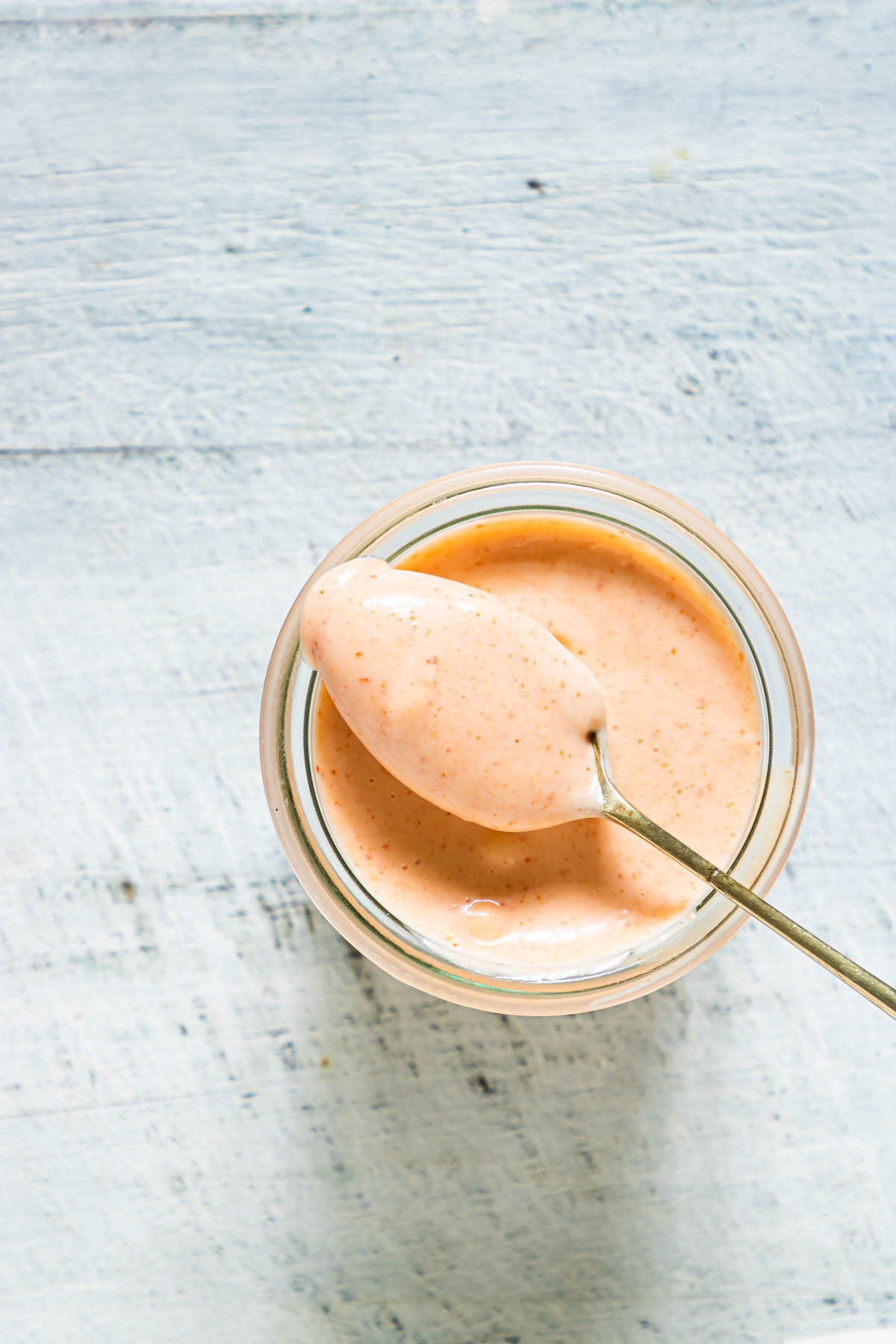 top down view of the completed sriracha aioli in a jar with a spoon removing one serving