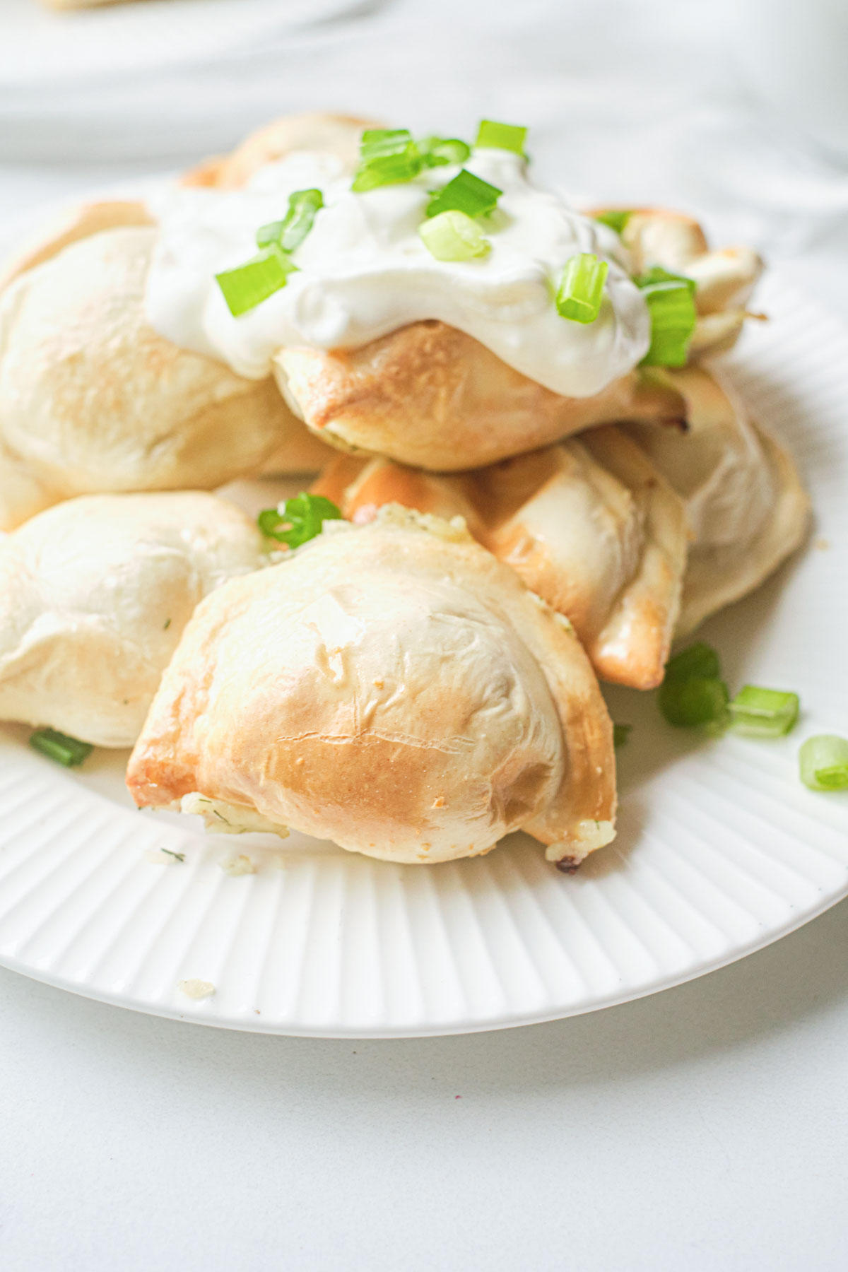 a plate of the finished air fryer frozen pierogies topped with sour cream and green onions