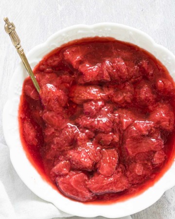 a bowl of instant pot strawberry compote with a spoon tucked in