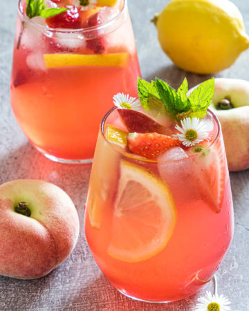 close up up of fresh peach lemonade on a table with fruit
