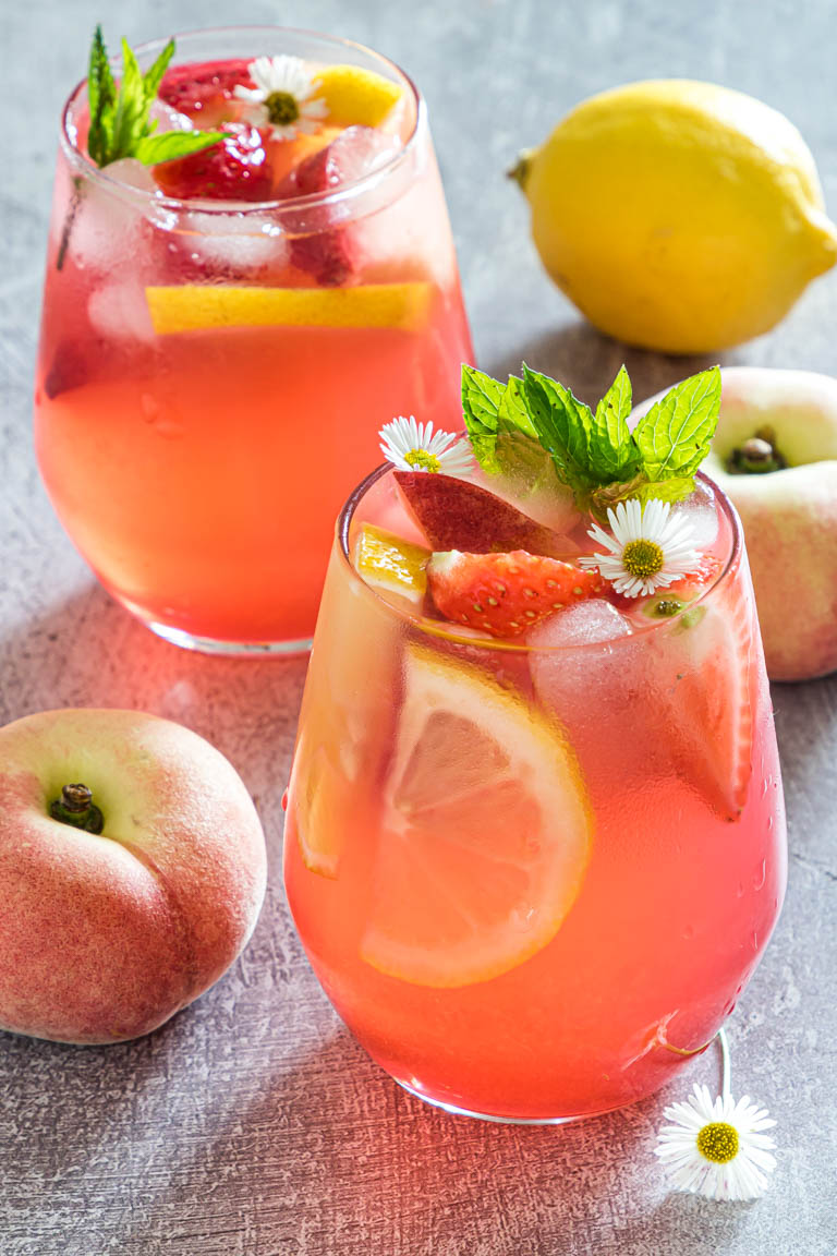 close up up of fresh peach lemonade on a table with fruit