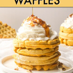 A stack of pumpkin waffles on a plate topped with whipped cream