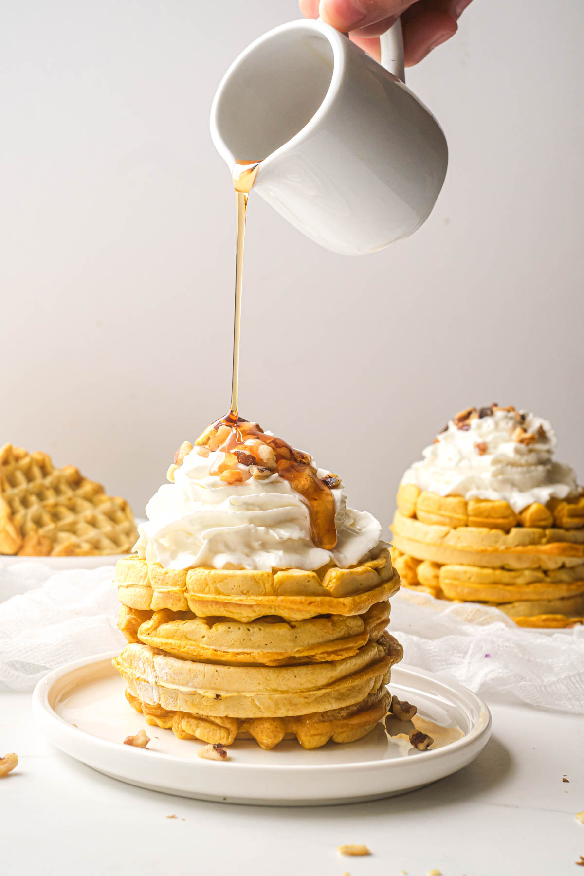 syrup being poured on top of a stack of pumpkin waffles