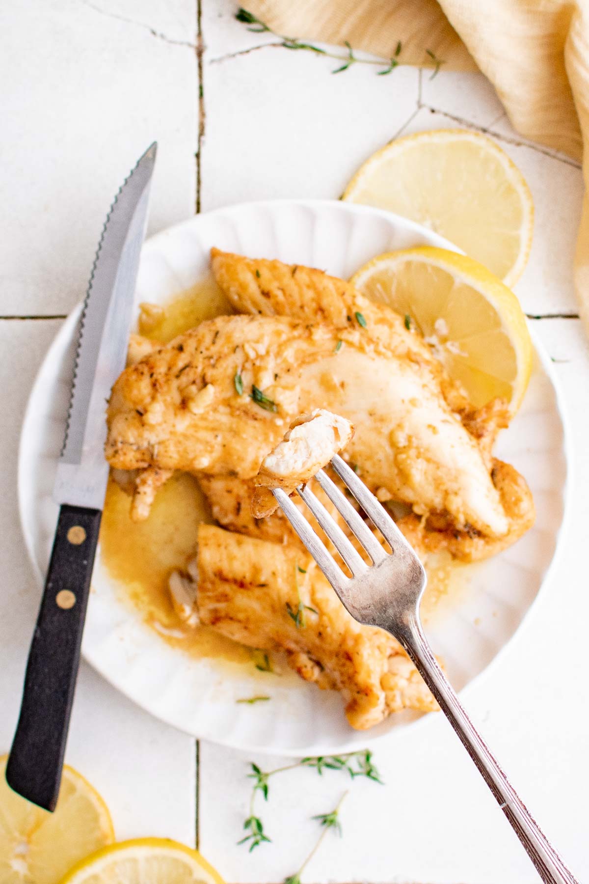 a plate of lemon garlic butter chicken tenders served with lemon wedges and utensils
