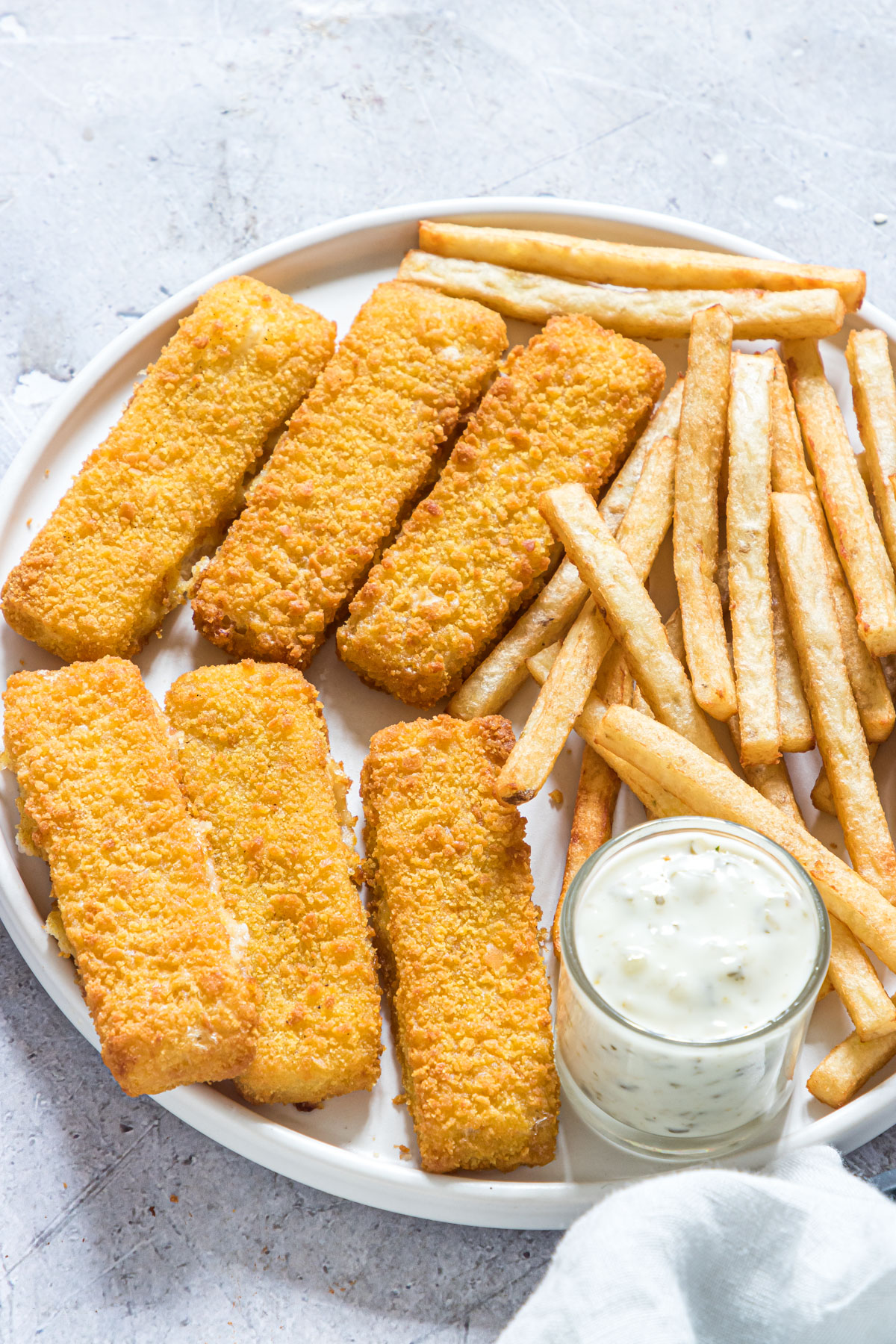 the completed air fryer frozen fish sticks served with french fries and tartar sauce