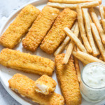 a plate filled with air fryer frozen fish sticks, french fries and tartar sauce