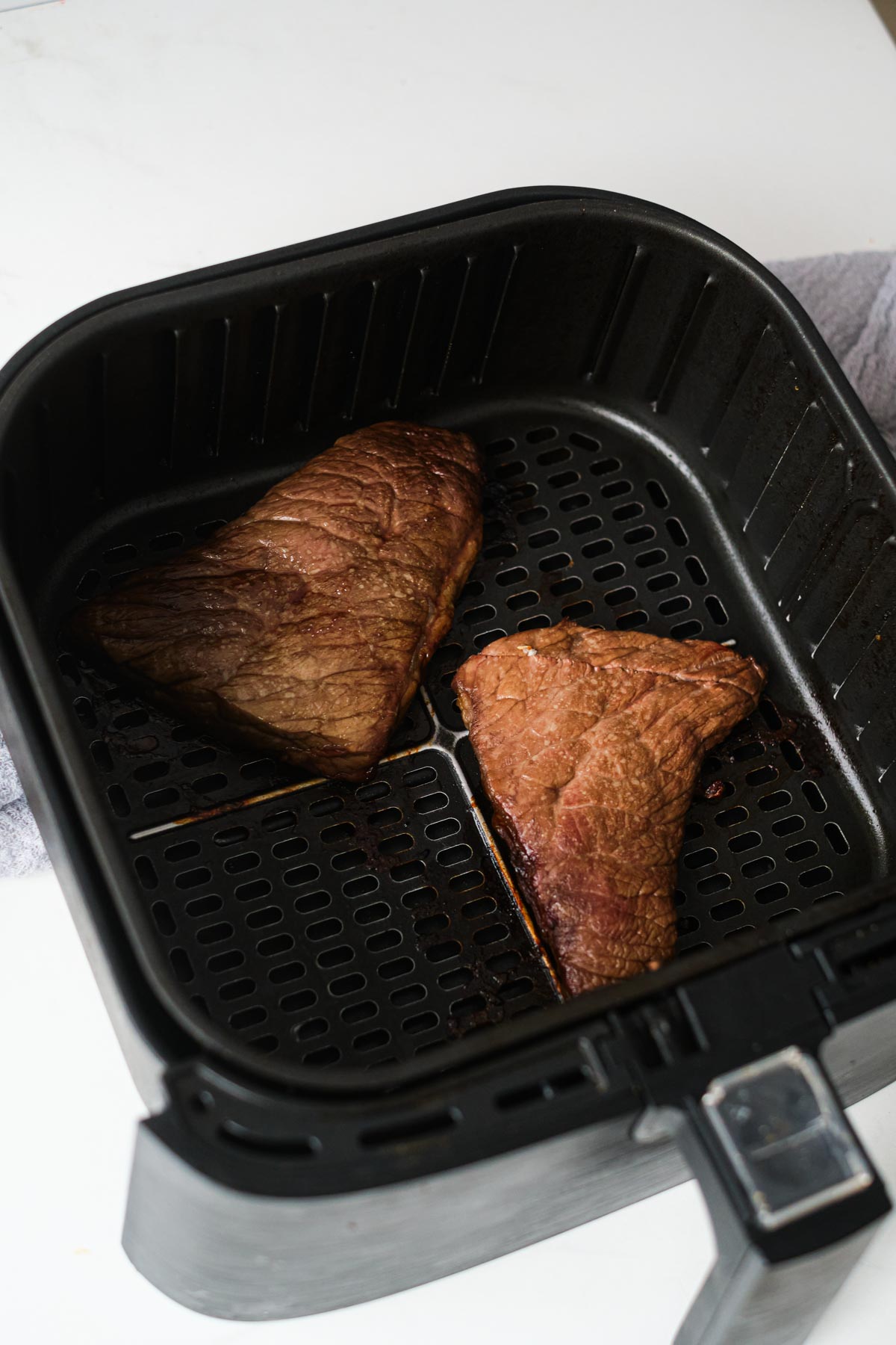 two portions of steak in the air fryer basket