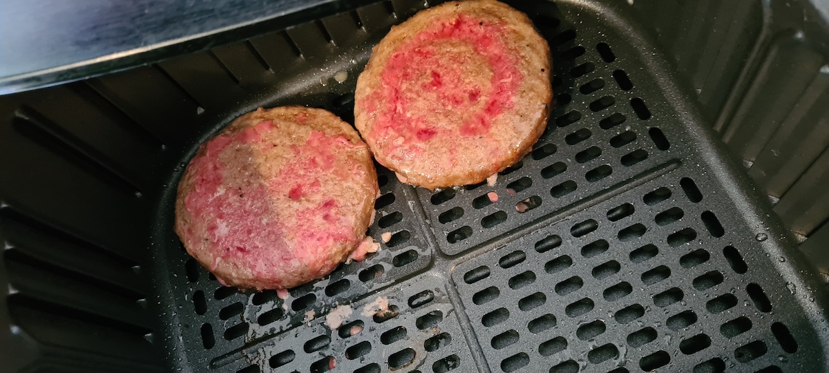 two of the frozen hamburger patties in air fryer