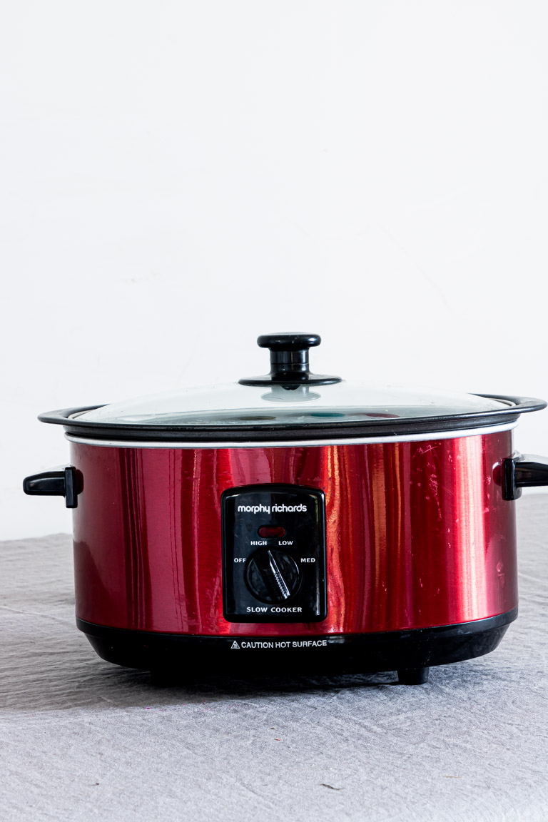 a red slow cooker on a countertop