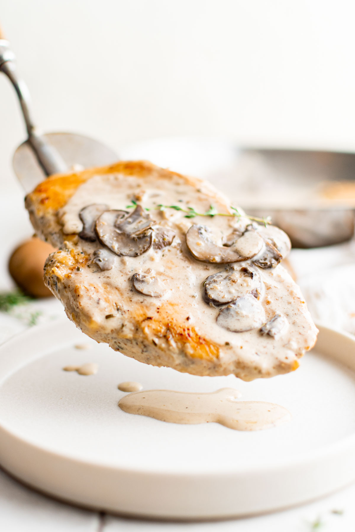 one portion of instant pot chicken and mushrooms being put onto a white dinner plate