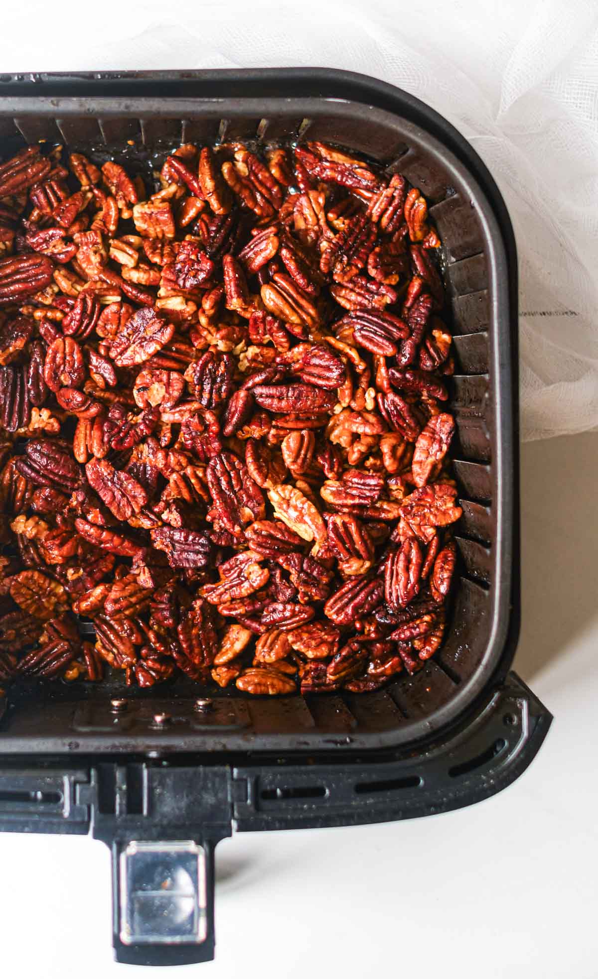 close up view of the air fryer pecans inside the air fryer basket