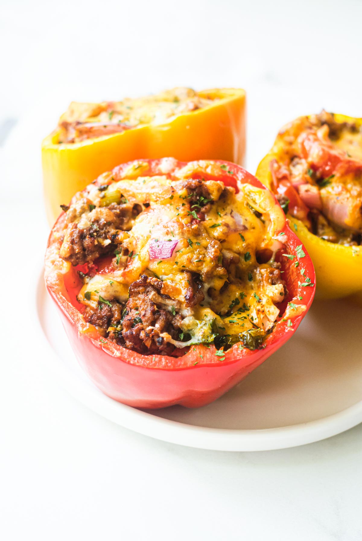 three cooked air fryer stuffed peppers on a white serving platter