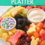 a platter with sliced fruit and rammekins of M&Ms and yogurt dip