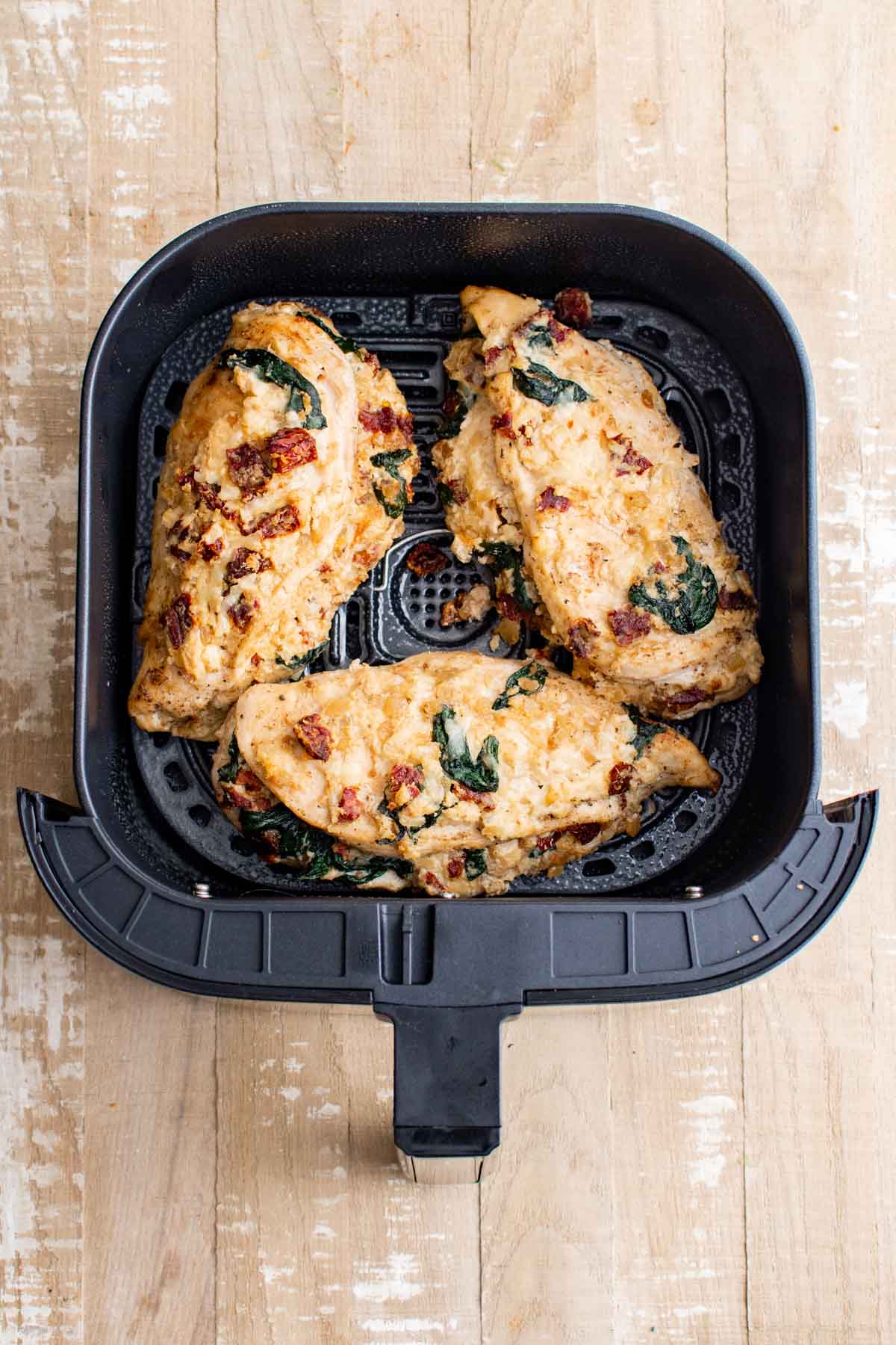 top down view of the cooked air fryer stuffed chicken breast inside the air fryer basket