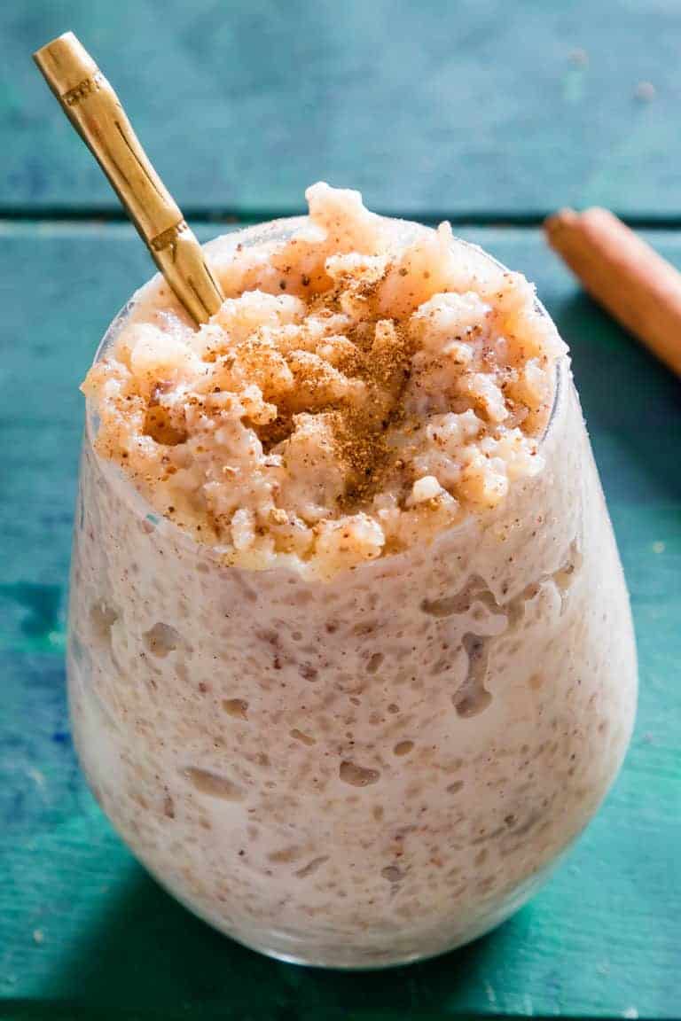 Instant Pot Arroz Con Leche served in a glass with a gold spoon and cinnamon stick