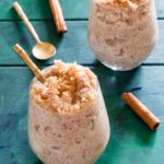 two servings of Instant Pot Arroz Con Leche (rice pudding) served with gold spoons and cinnamon sticks