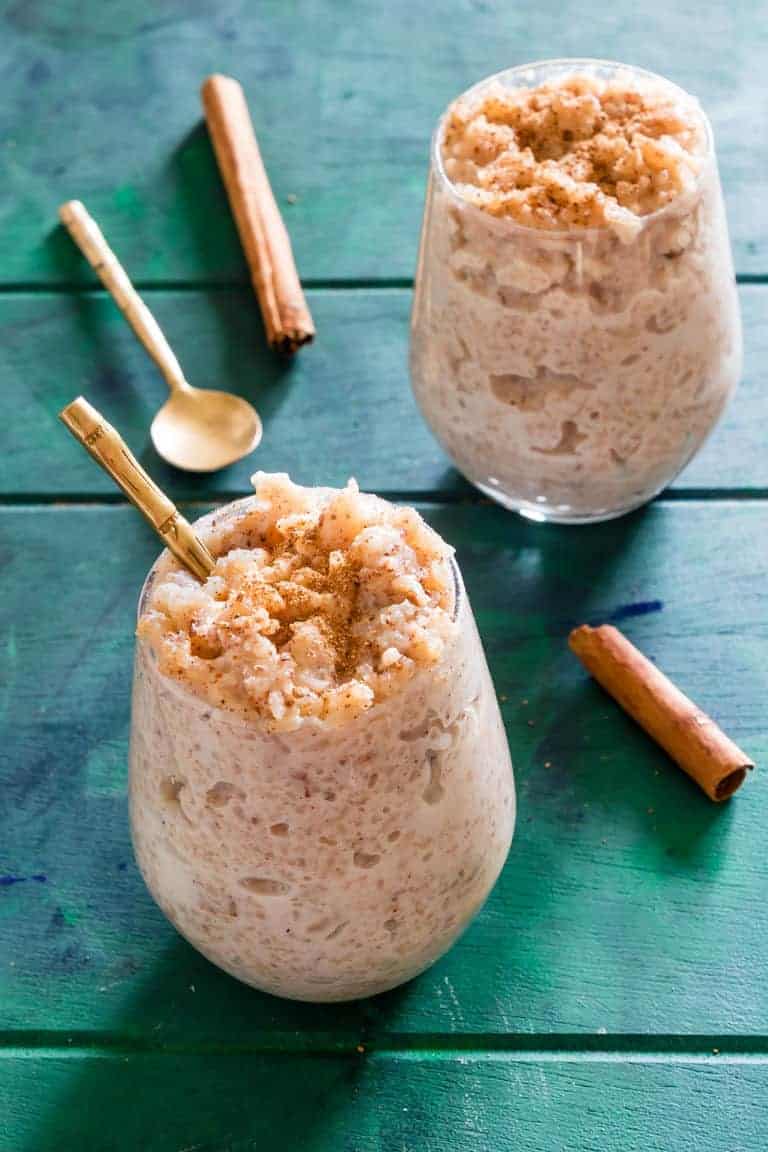 two servings of Instant Pot Arroz Con Leche (rice pudding) served with gold spoons and cinnamon sticks