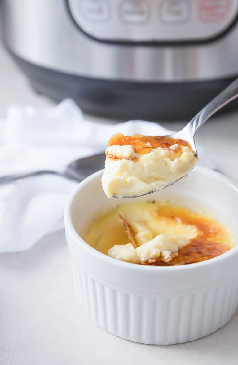 close up of a serving of Instant Pot Creme Brulee with a spoon scooping out one bite.