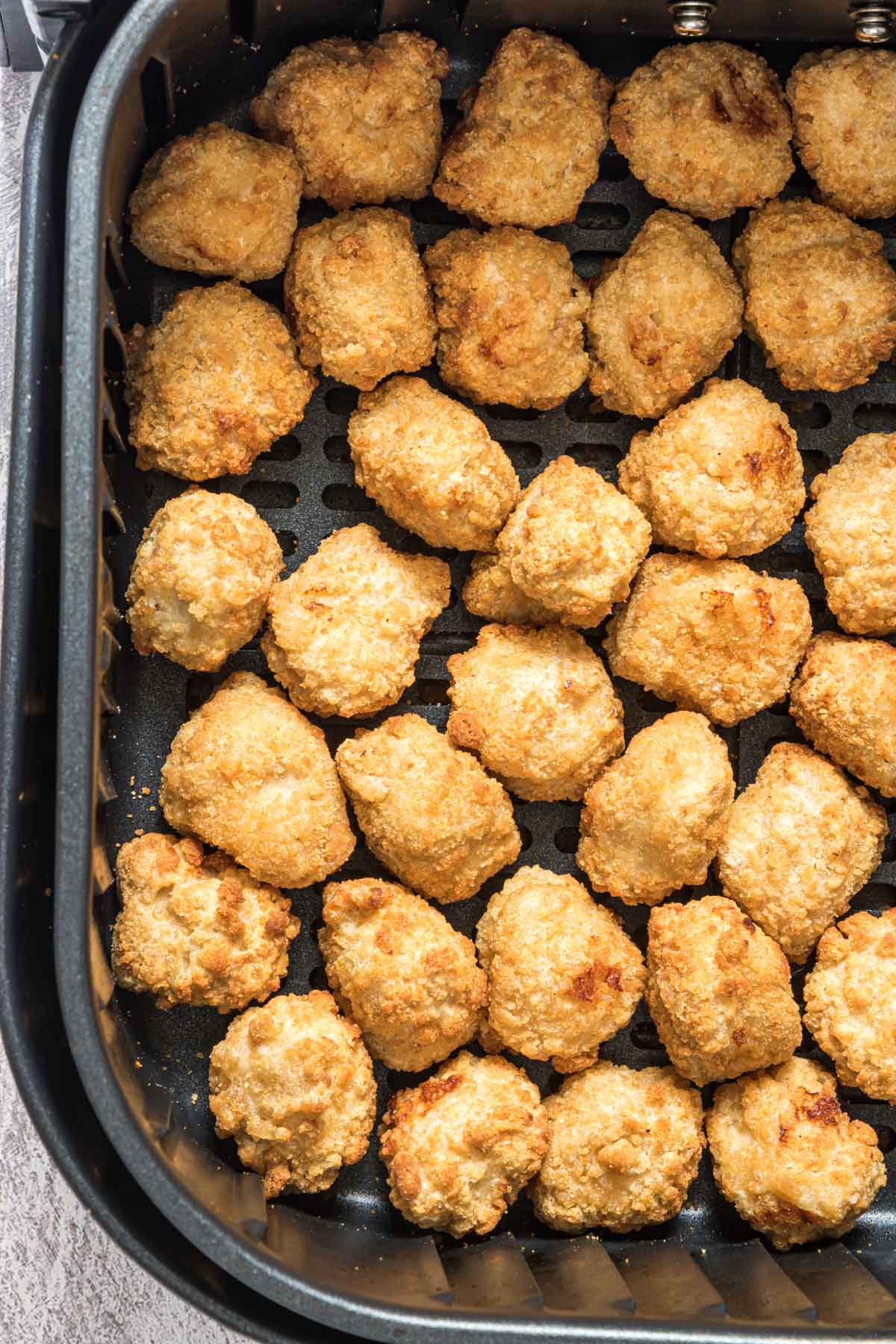 close up view of reheat chicken nuggets in air fryer basket