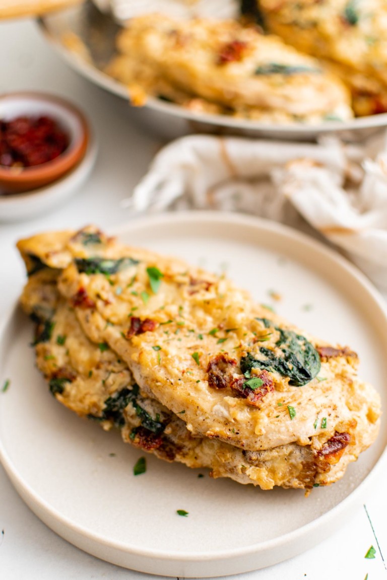 the completed spinach stuffed chicken breast on a white plate