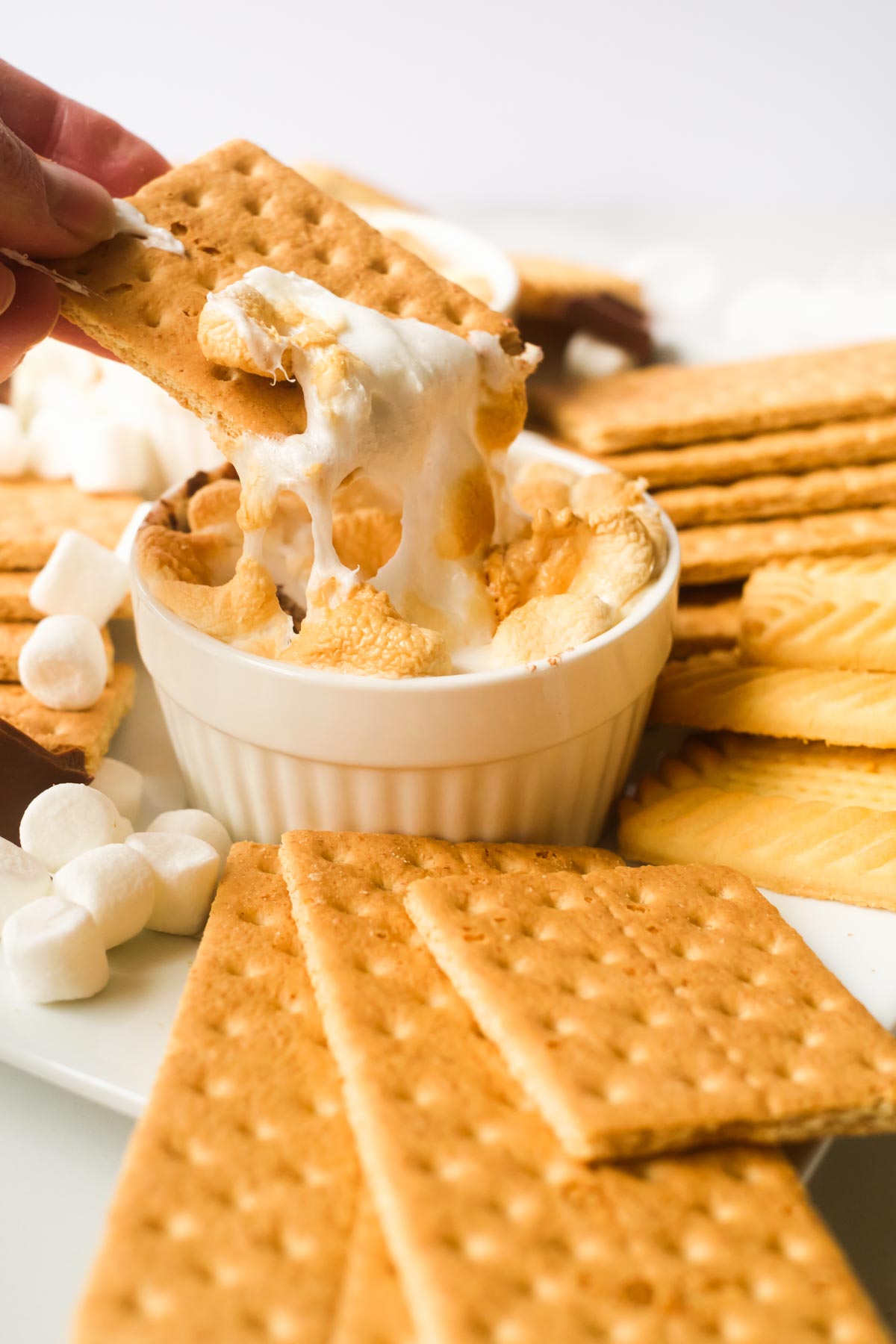 a hand dipping one graham cracker into the air fryer smores dip